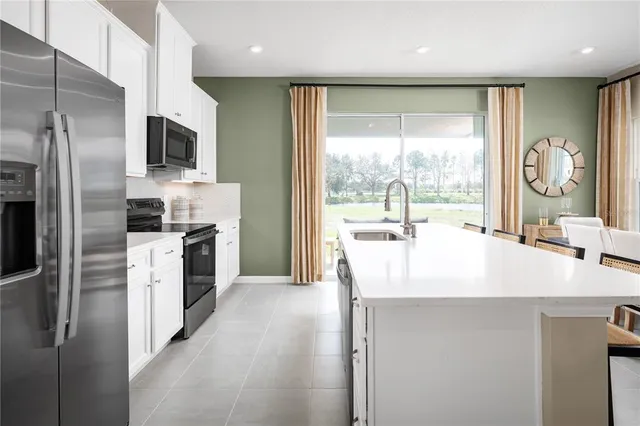 a kitchen with a sink a counter top space stainless steel appliances a large window and cabinets