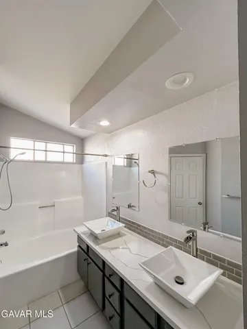 a bathroom with a sink double vanity granite tub shower and a mirror