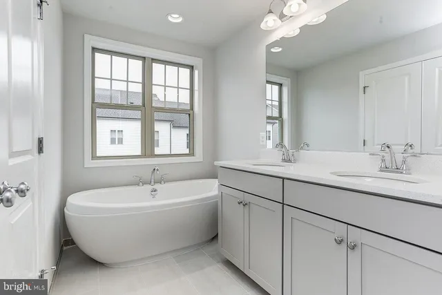 a bathroom with a double vanity sink a mirror and a bathtub