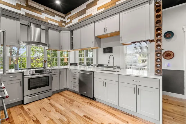 a kitchen with stainless steel appliances a sink dishwasher stove refrigerator and cabinets with wooden floor