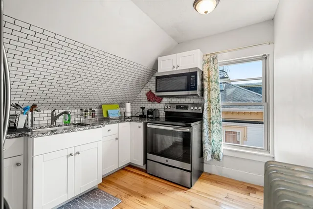 a kitchen with a sink wooden floor and stainless steel appliances