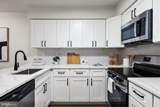 a kitchen with stainless steel appliances granite countertop a refrigerator a stove a sink dishwasher and a dining table with wooden floor