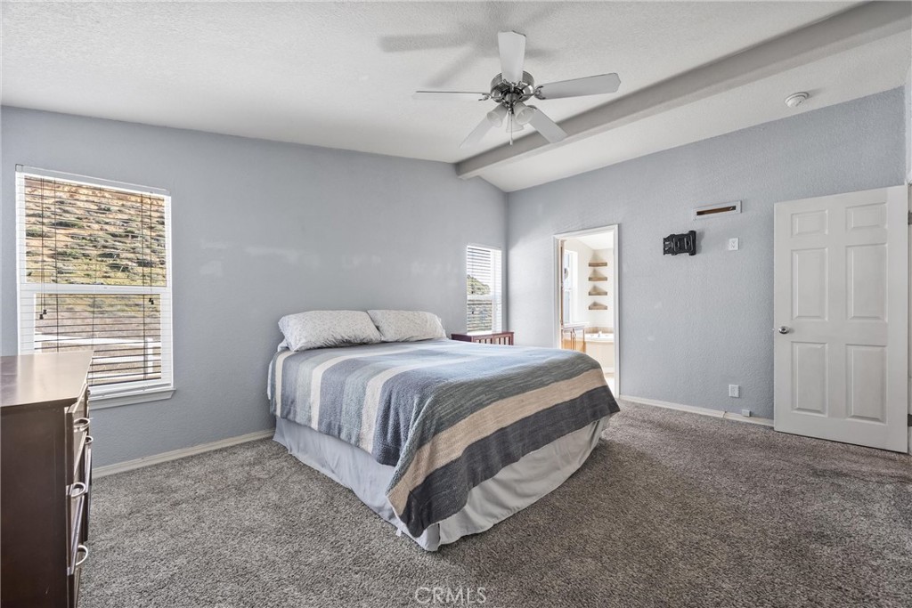 990 Mesa Valley Road Lebec, CA 93243 - Photo 15 of 38 a spacious bedroom with a bed a chandelier and a window