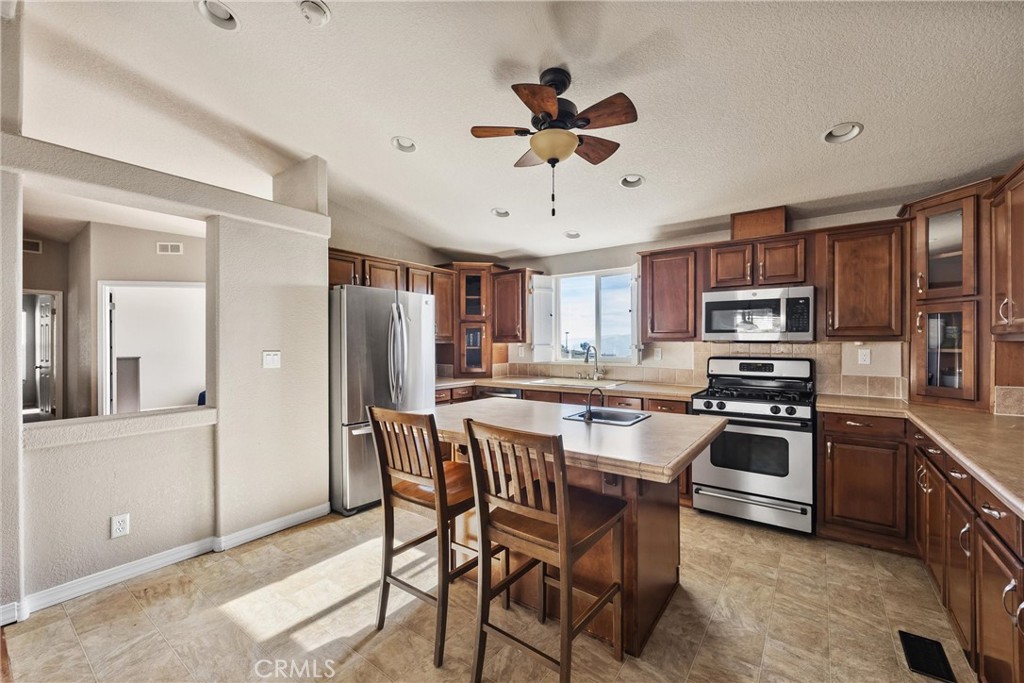 990 Mesa Valley Road Lebec, CA 93243 - Photo 9 of 38 a kitchen with stainless steel appliances granite countertop a stove top oven a sink a refrigerator with a dining table and chairs