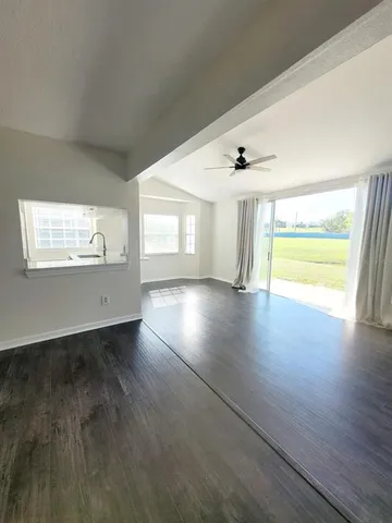 a view of an empty room with a window and wooden floor