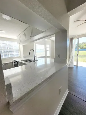 a kitchen with kitchen island a sink wooden floor and a large window