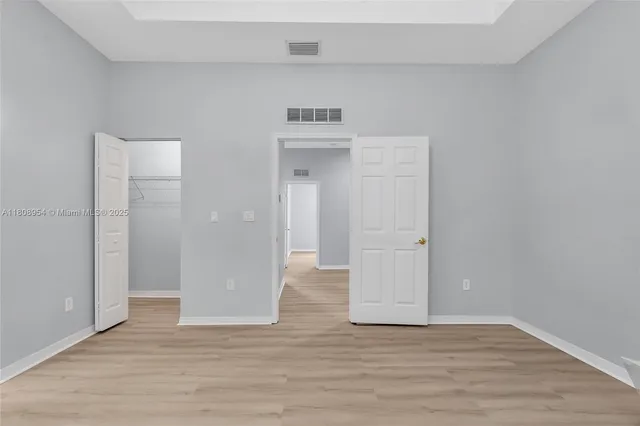 a view of an empty room with wooden floor and closet