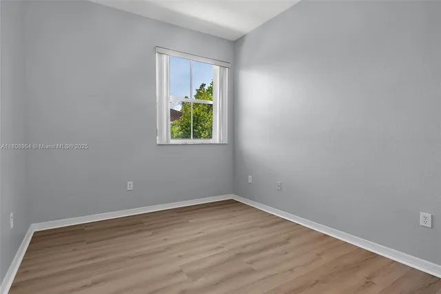 a view of an empty room with window and wooden floor