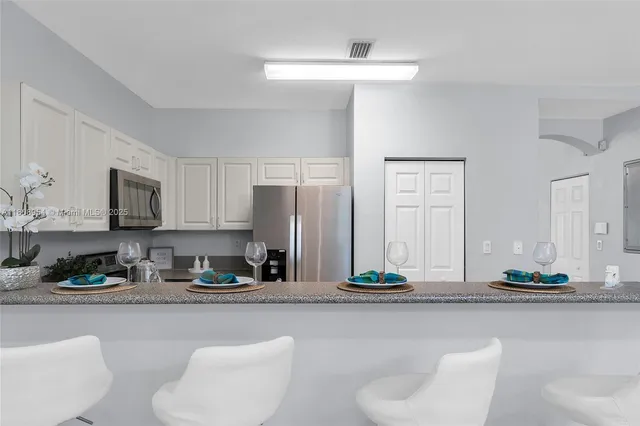 a kitchen with stainless steel appliances granite countertop a sink a stove and a refrigerator