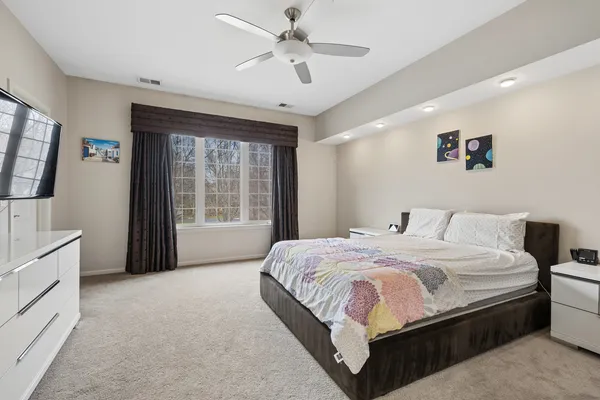 a bedroom with a large bed and a chandelier fan