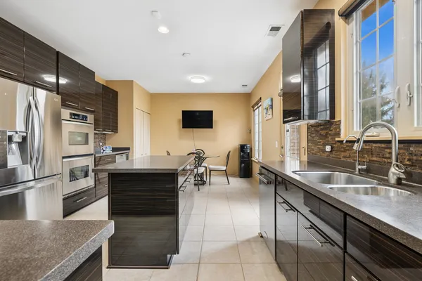 a kitchen with stainless steel appliances granite countertop a sink a stove and a refrigerator
