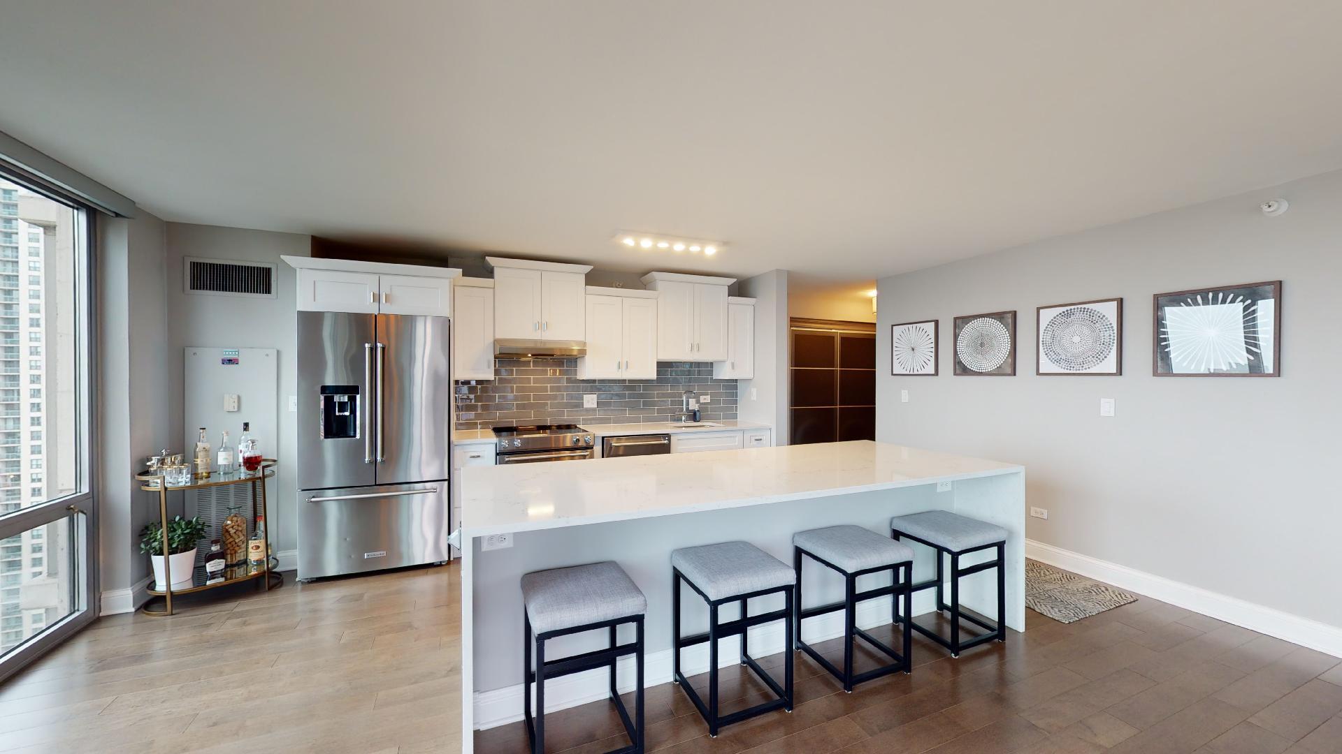 2 East Erie Street, Unit 3605 Chicago, IL 60611 - Photo 12 of 30 a kitchen with stainless steel appliances refrigerator wooden floor dining table and chairs