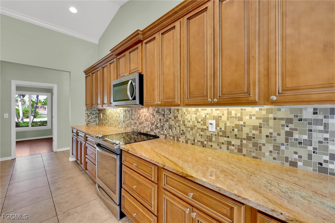 17040 Pleasure Road Cape Coral, FL 33909 - Photo 11 of 38 a kitchen with granite countertop a sink stainless steel appliances wooden floor and a counter top space