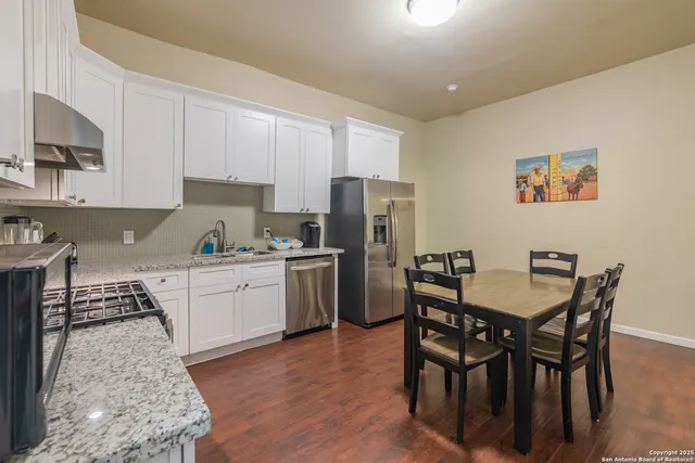 a kitchen with a dining table chairs refrigerator and cabinets
