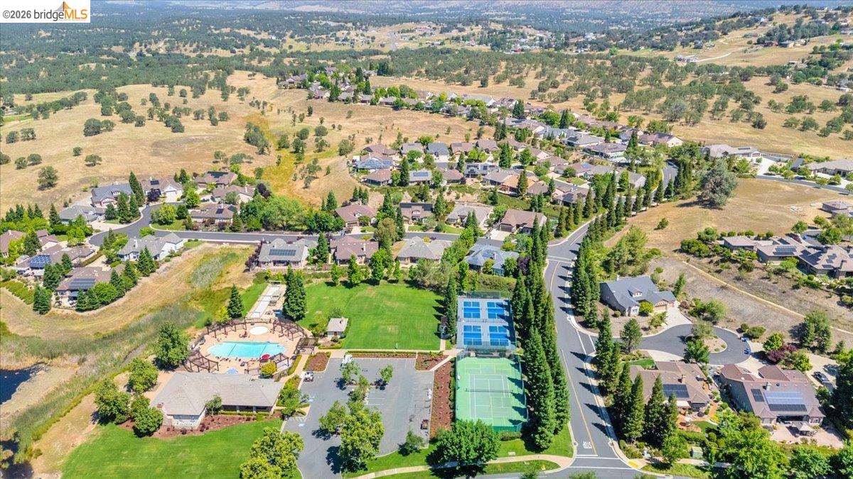 158 Rock Ridge Lane Copperopolis, CA 95228 - Photo 70 of 72 Aerial view of a residential community featuring a swimming pool area with a trellised patio, two tennis courts, and a large green space