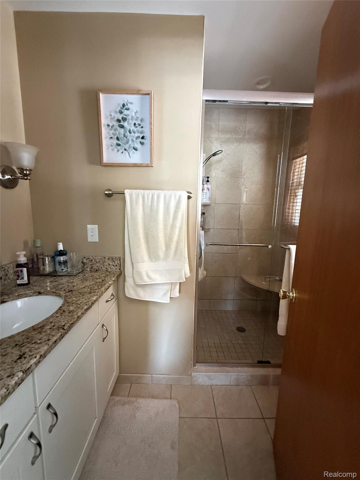 3668 East Allen Road Howell, MI 48855 - Photo 10 of 18 Bathroom featuring a granite-topped vanity with white cabinetry, an undermount sink, and a glass-enclosed shower with tiled walls and a built-in bench