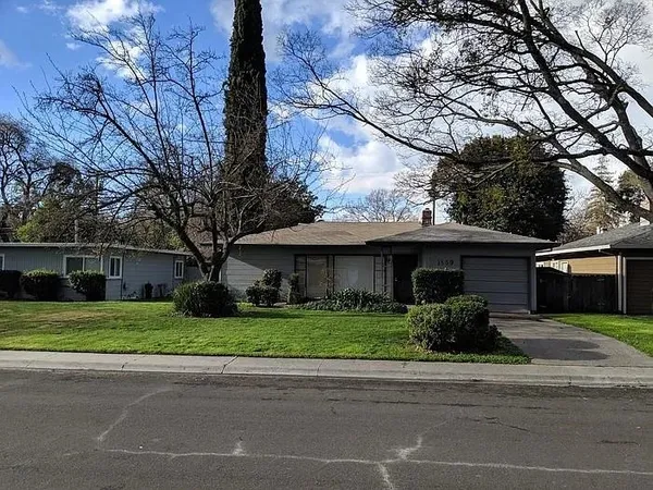 a front view of a house with a garden and trees