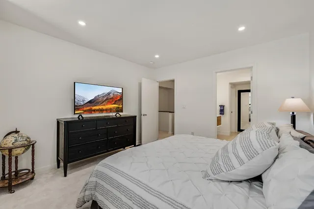 a bedroom with a bed and a flat tv screen on dresser
