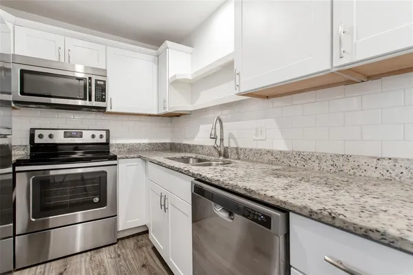 a kitchen with stainless steel appliances granite countertop a sink stove and microwave