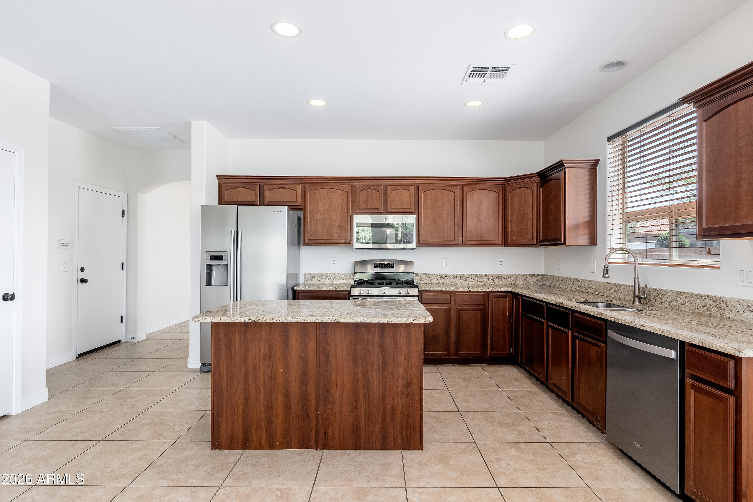 4317 East Folgers Road Phoenix, AZ 85050 - Photo 9 of 40 a kitchen with stainless steel appliances granite countertop a sink counter space cabinets and a large window
