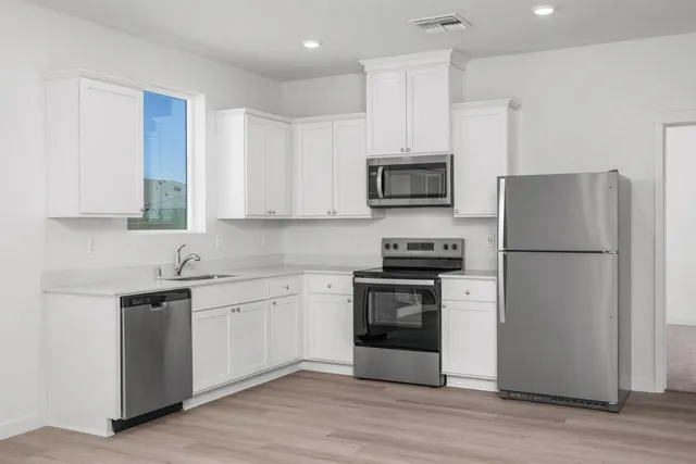 a kitchen with stainless steel appliances granite countertop a refrigerator stove a sink and a microwave