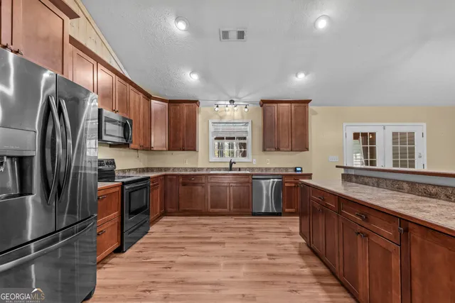 a large kitchen with stainless steel appliances granite countertop a stove sink refrigerator and cabinets