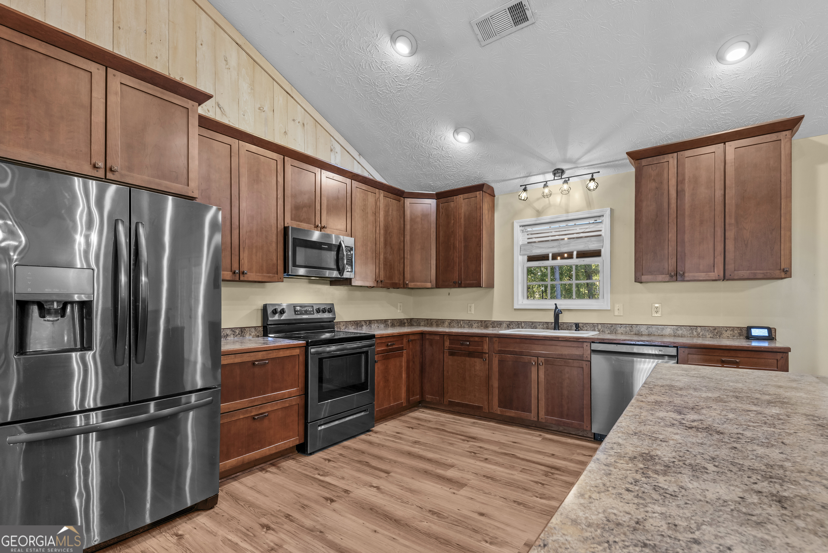 384 Scuffleboro Road Southeast Eatonton, GA 31024 - Photo 13 of 48 a kitchen with stainless steel appliances granite countertop a refrigerator a sink dishwasher a stove top oven a refrigerator with wooden cabinets and wooden floor