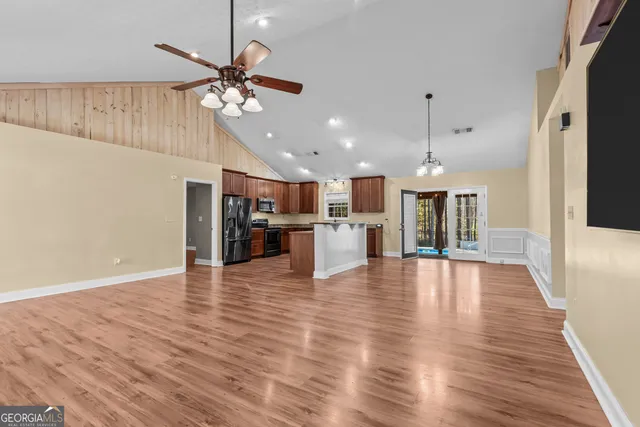 a view of an empty room with kitchen appliances and a ceiling fan