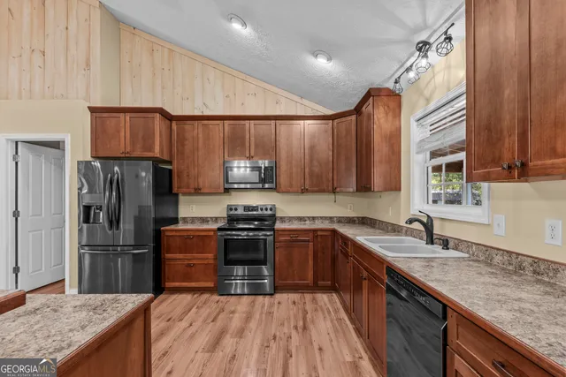 a kitchen with granite countertop wooden cabinets a stove top oven and stainless steel appliances