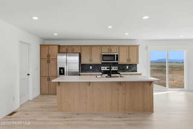 a view of kitchen with stainless steel appliances granite countertop refrigerator stove microwave and cabinets