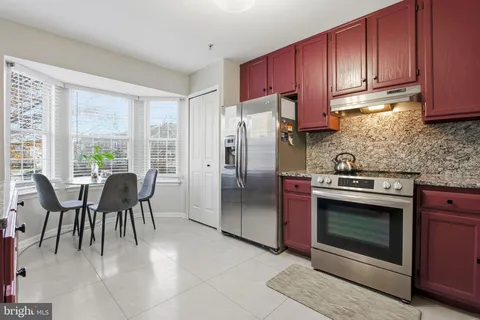 a kitchen with stainless steel appliances granite countertop a stove a refrigerator and wooden cabinets