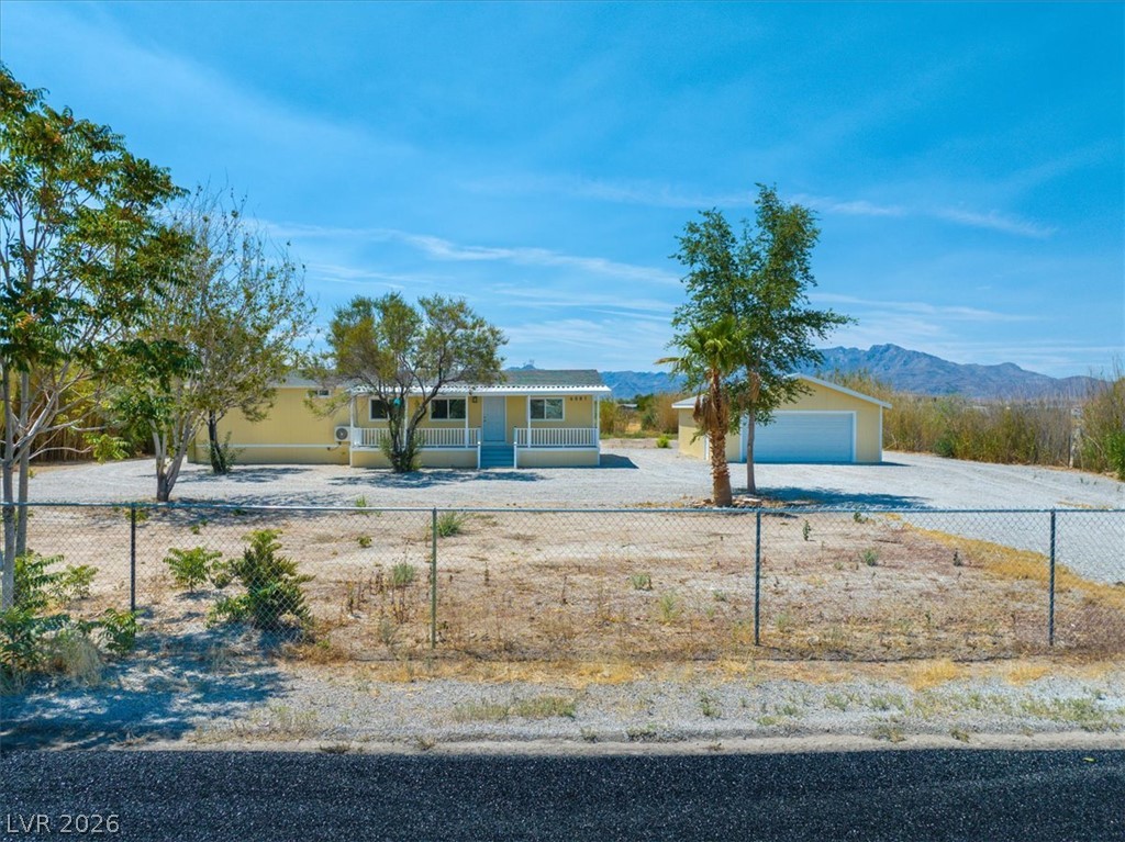 4081 Retread Road Pahrump, NV 89048 - Photo 85 of 98 A well-maintained residence with a detached garage sits on a spacious, fenced lot offering desert landscape views and a front porch.