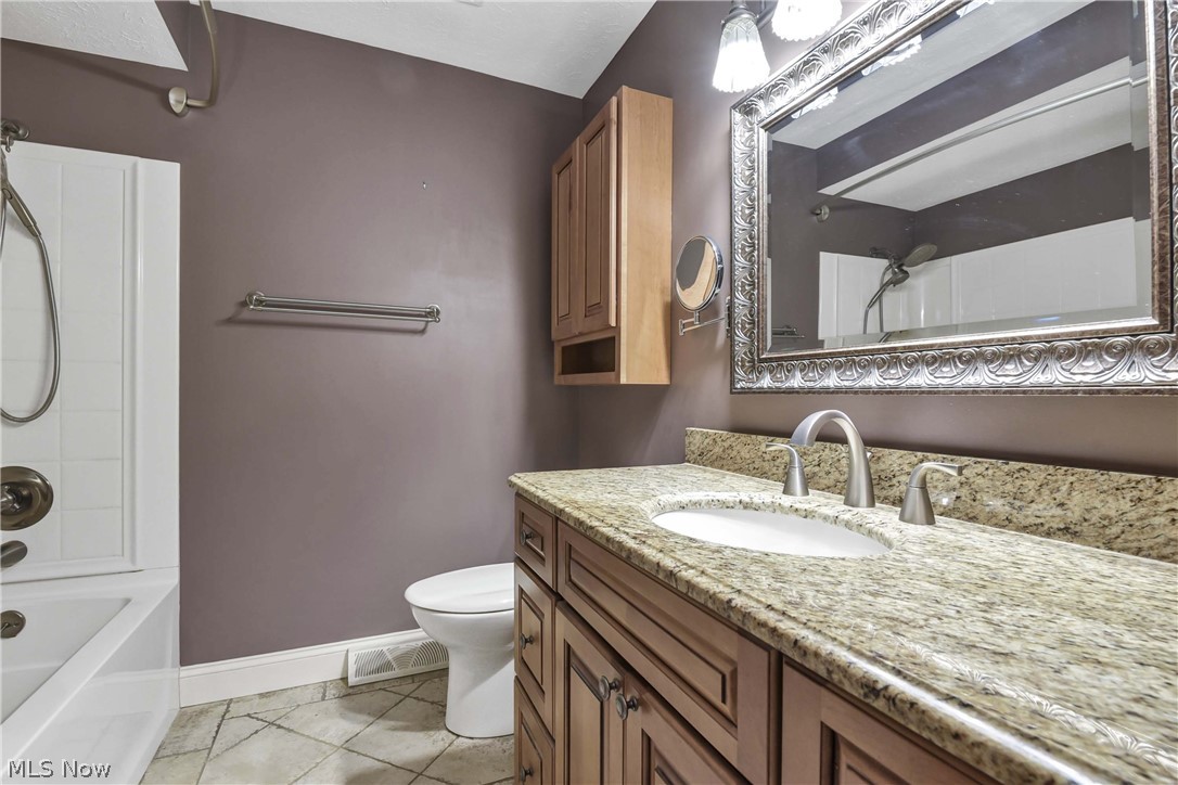 7350 Ames Road Parma, OH 44130 - Photo 24 of 50 Full bathroom on first floor with kraftmaid vanity, granite counter, mirror, light fixture, tile floor, toilet and kraftmaid storage cabinet