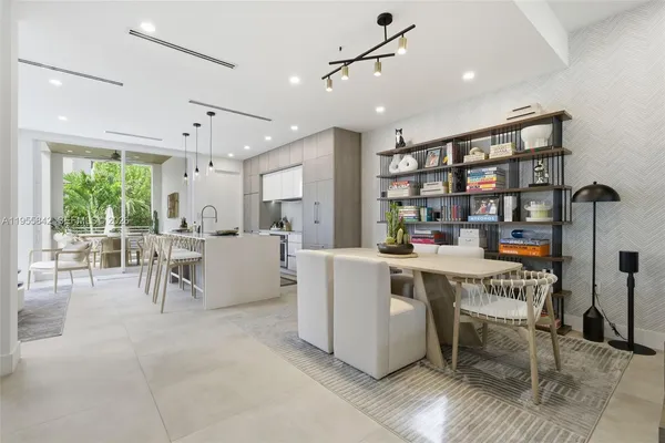 a living room with stainless steel appliances furniture a rug and a large window