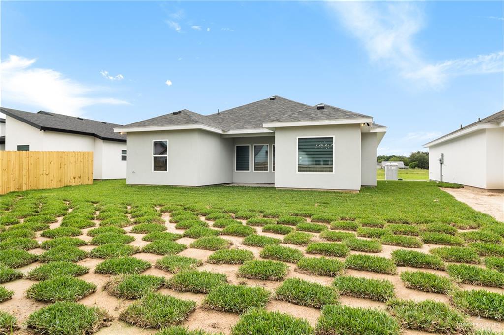 18054 Spruce Street Combes, TX 78552 - Photo 23 of 25 Rear exterior featuring a light gray stucco finish and a dark shingle roof