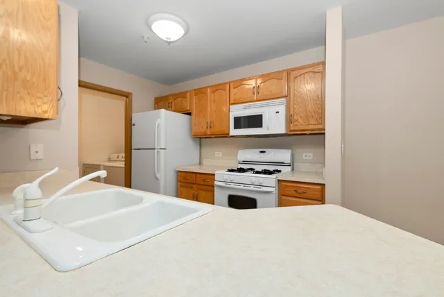 a kitchen with stainless steel appliances a stove top oven a sink a refrigerator white cabinets and wooden floor