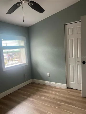 an empty room with wooden floor cabinet and windows