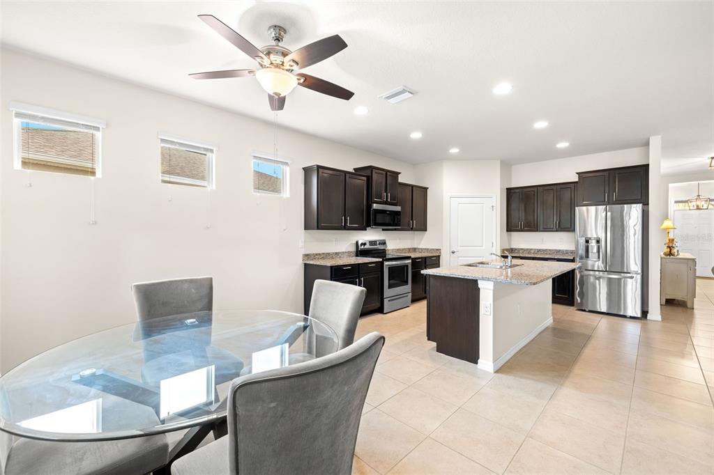 13562 Paddington Way Spring Hill, FL 34609 - Photo 7 of 39 a kitchen with a refrigerator a microwave a stove a sink dishwasher a dining table and chairs with wooden floor