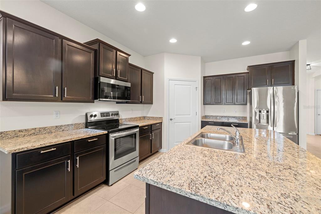13562 Paddington Way Spring Hill, FL 34609 - Photo 10 of 39 a kitchen with stainless steel appliances granite countertop a sink stove microwave and refrigerator