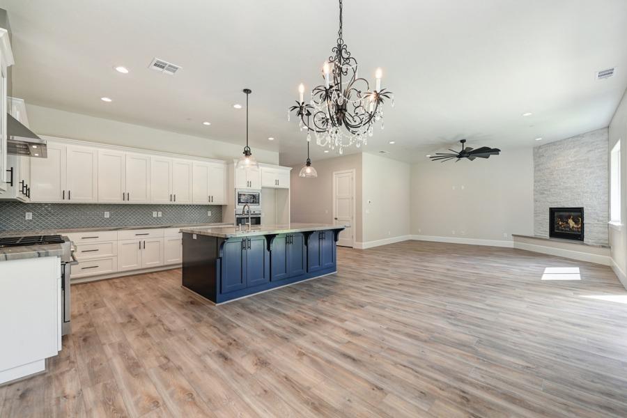 a large kitchen with stainless steel appliances granite countertop a oven and a wooden floors