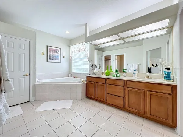 a spacious bathroom with a double vanity sink mirror and bathtub