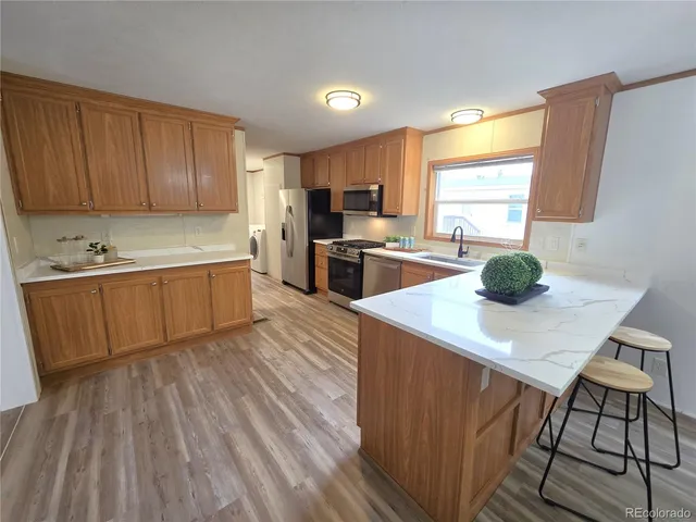 a kitchen with wooden floors a sink stainless steel appliances and cabinets