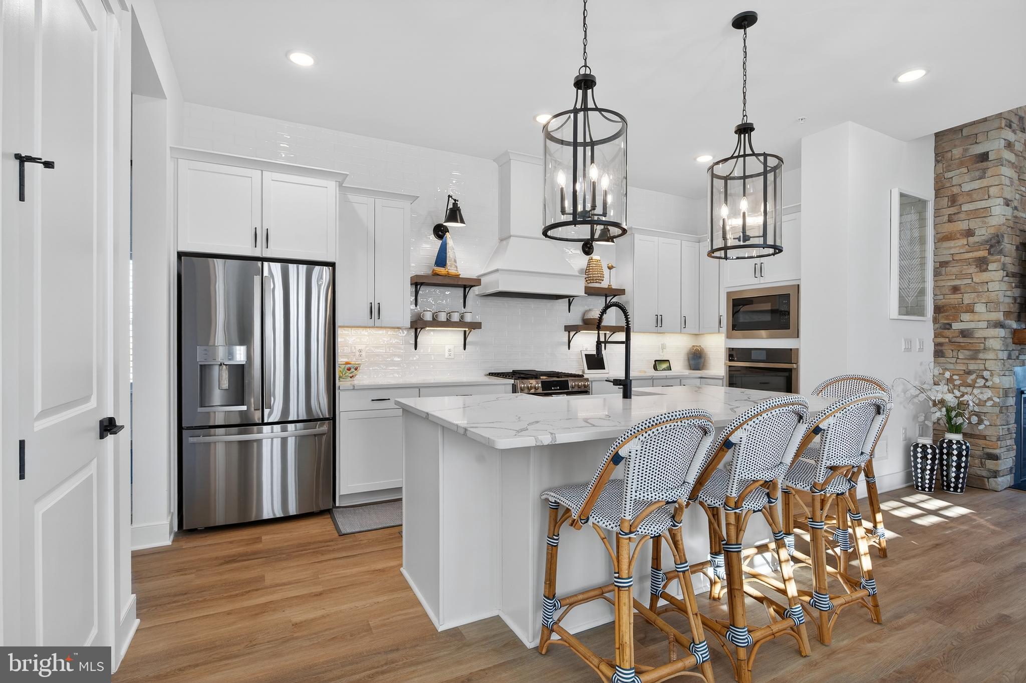 528 Warbler Way Chester, MD 21619 - Photo 5 of 29 a kitchen with stainless steel appliances granite countertop a refrigerator a sink dishwasher a stove and a dining table with wooden floor