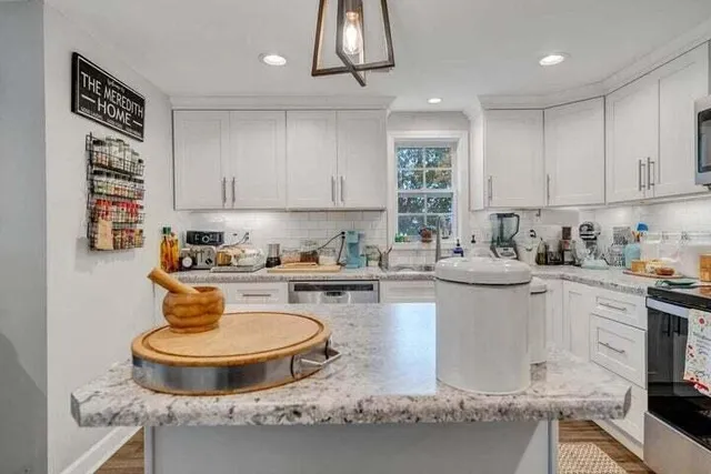 a kitchen with granite countertop white cabinets and stainless steel appliances