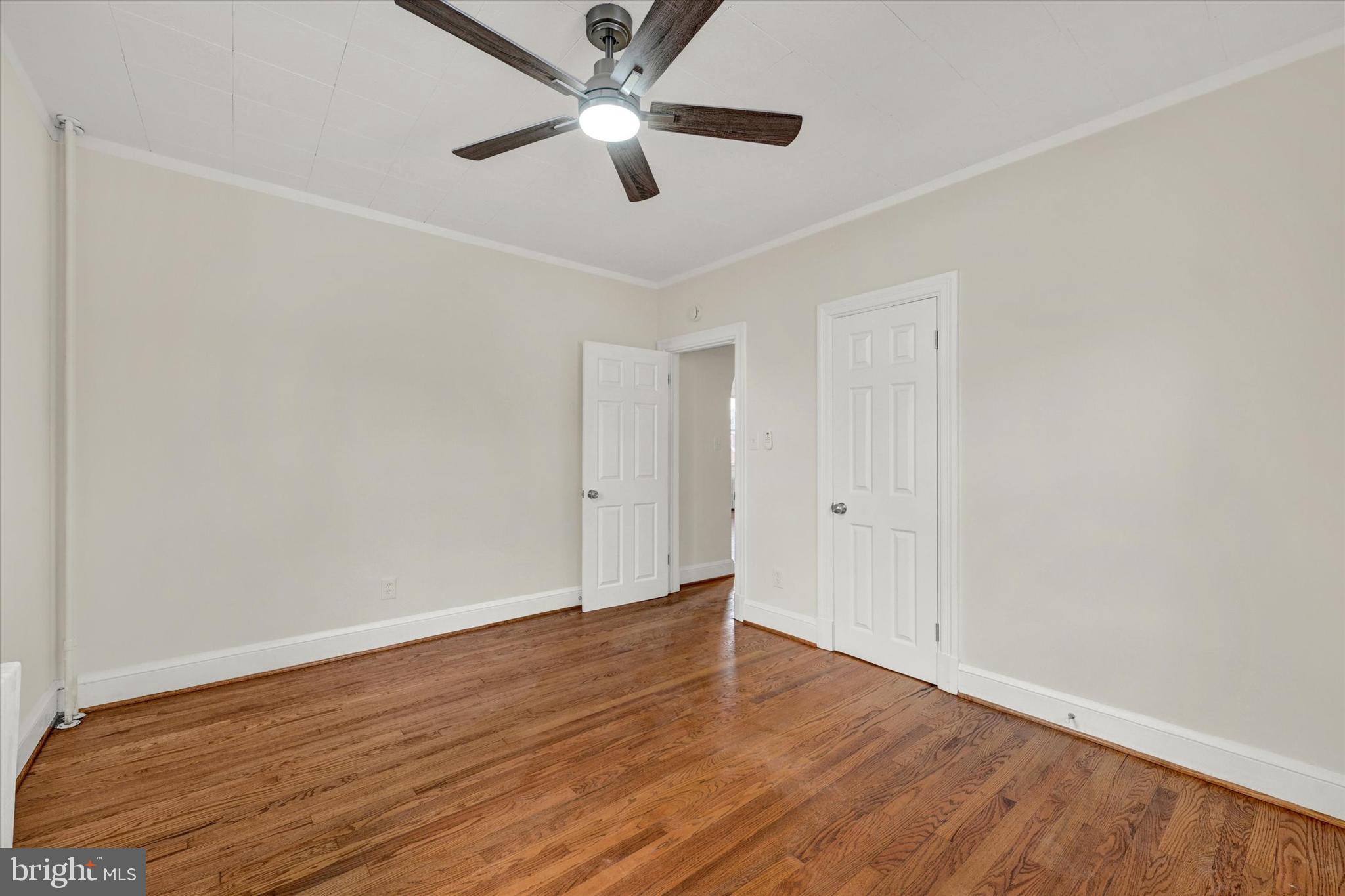 1032 Elm Ridge Avenue Baltimore, MD 21229 - Photo 11 of 28 an empty room with wooden floor and a ceiling fan