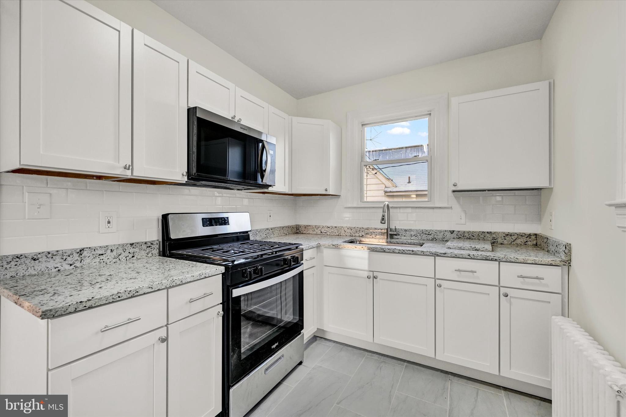 1032 Elm Ridge Avenue Baltimore, MD 21229 - Photo 16 of 28 a kitchen with granite countertop white cabinets sink and stainless steel appliances