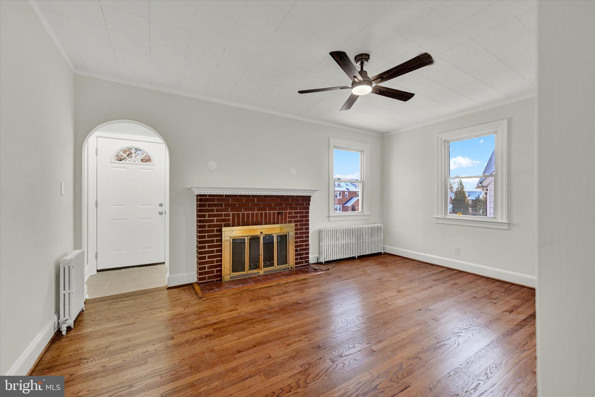 1032 Elm Ridge Avenue Baltimore, MD 21229 - Photo 5 of 28 an empty room with wooden floor a ceiling fan and windows