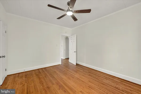 an empty room with wooden floor and a ceiling fan