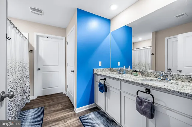 a bathroom with a granite countertop sink a toilet and shower