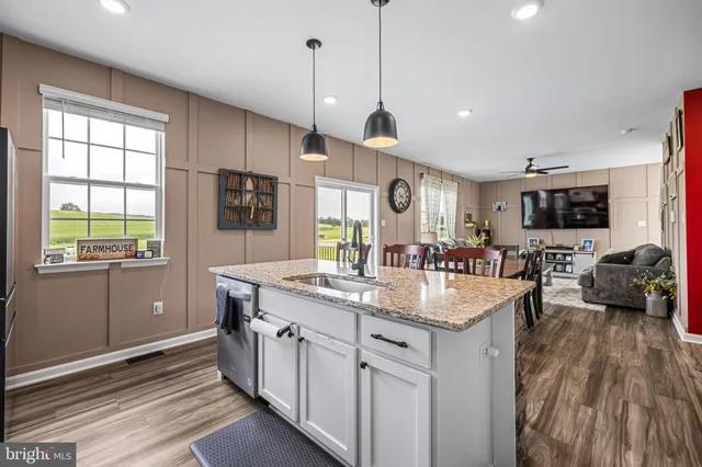 a kitchen with kitchen island granite countertop a sink appliances and cabinets